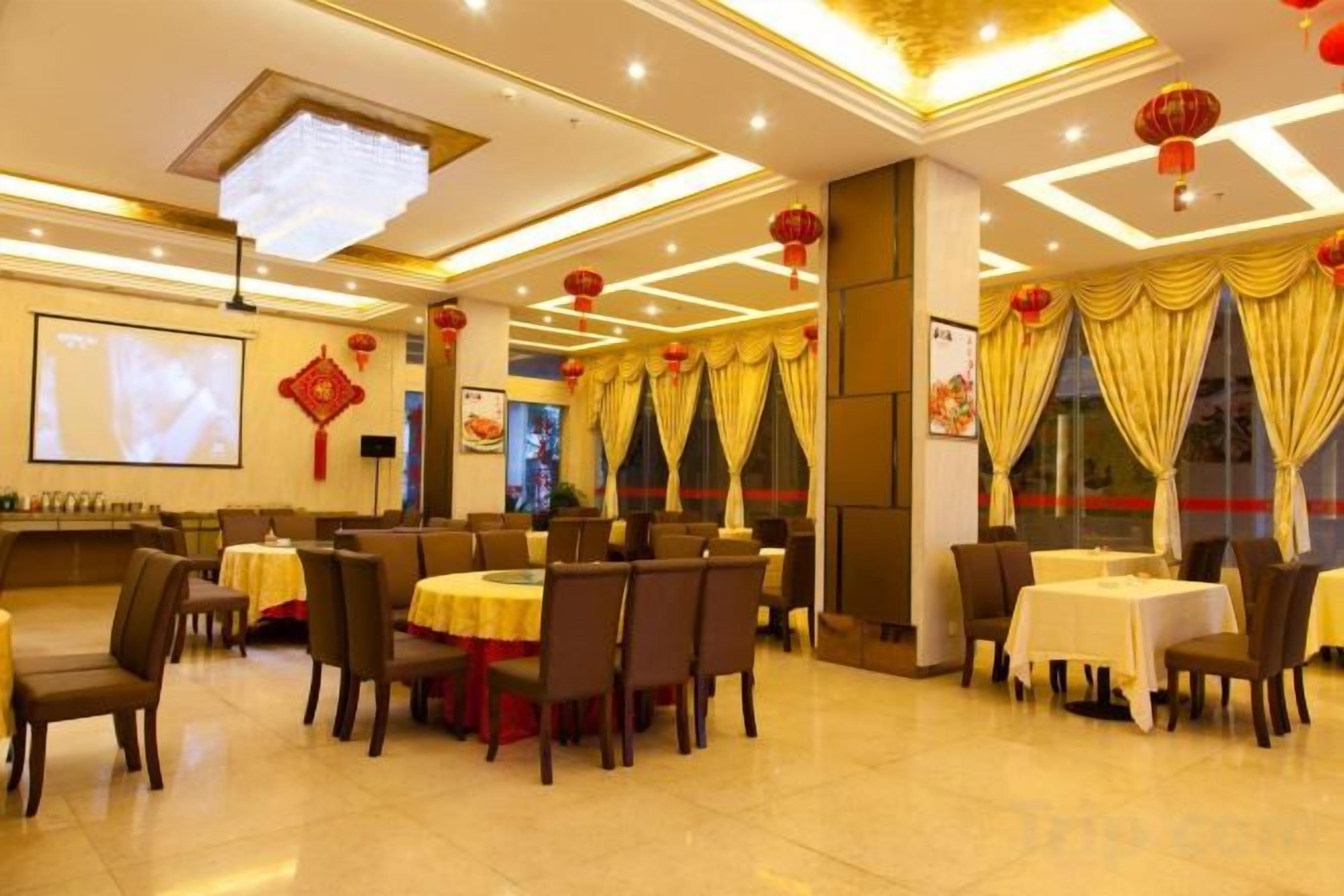 A restaurant with multiple tables and chairs, a projection screen, and traditional decorations.