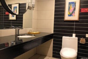 A modern bathroom with a black countertop, a white sink, a mirror, and a toilet. - Beichen Hotel (Haikou)