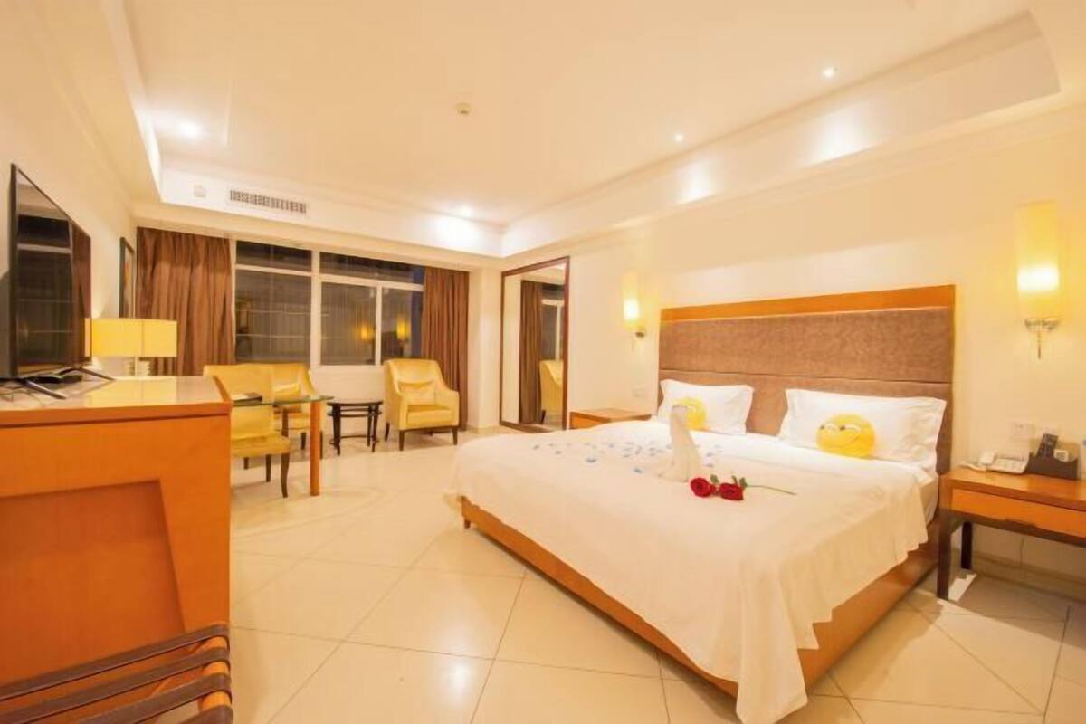 A hotel room with a bed, a desk, a chair, and a window.