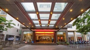 A hotel entrance with a glass canopy and a red-lit reception area. - Beichen Hotel (Haikou)