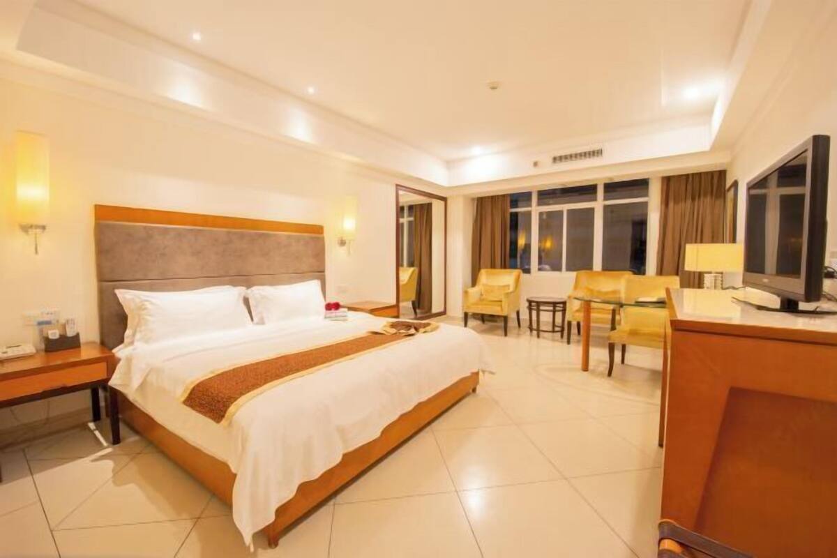 A hotel room with a large bed, a desk, a chair, and a television.