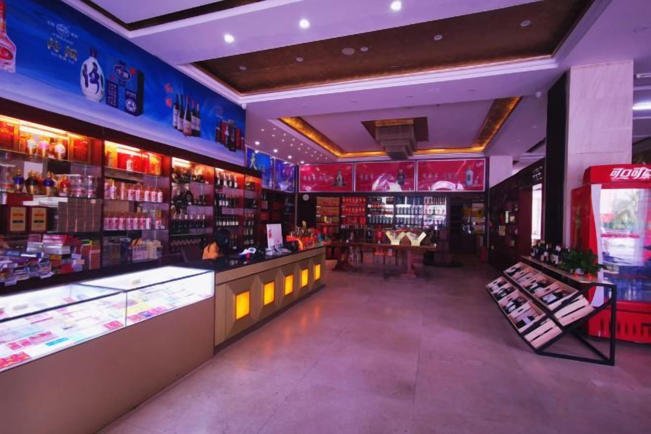 A brightly lit retail store with shelves stocked with various products, a display counter, and promotional posters on the walls.