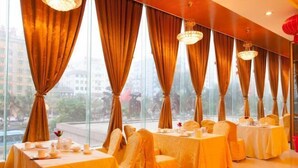 A restaurant with tables set for dining, large windows with curtains, and chandeliers. - Beichen Hotel (Haikou)