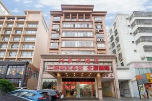 Ein mehrstöckiges Hotel mit markanter Fassade, Beschilderung und Parkplatz.