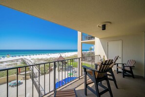 A balcony with a view of the beach, outdoor seating, and a pool area. - 1B 1B Beachfront Condo With Bunks - Phoenix 1 1024 (Orange Beach)