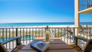 Ein Balkon mit Blick auf den Strand, eine Weinflasche und ein Buch.