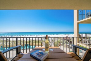 A balcony with a view of the beach, a bottle of wine, and a book. - 1B 1B Beachfront Condo With Bunks - Phoenix 1 1024 (Orange Beach)