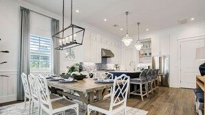 Una cocina moderna con armarios blancos, una mesa de comedor de madera y una isla central.