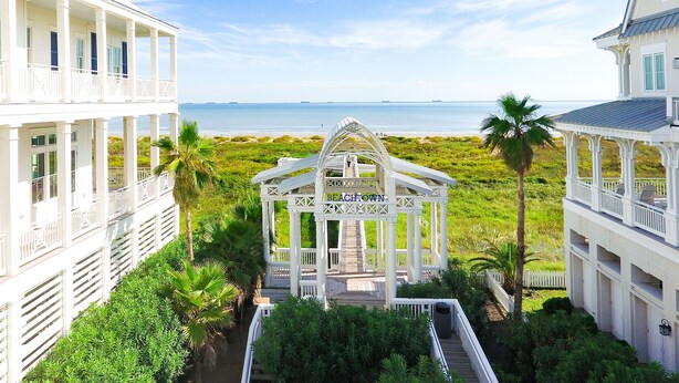 Una propiedad frente a la playa con un pabellón, varios balcones y abundante vegetación.