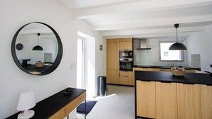Een moderne keuken met houten kastjes, een zwart aanrecht en een ronde spiegel.