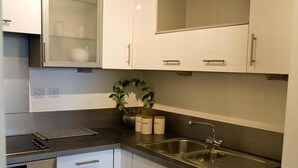 A modern kitchen with white cabinets, a stainless steel sink, and a built-in oven.