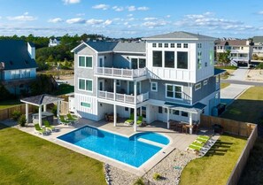 A two-story house with a swimming pool, a covered patio, and a fenced backyard. - Luxury Oceanview, Heated Pool, Theater, Pool Table (Corolla)
