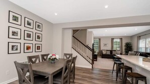 A modern kitchen with a dining area, wooden furniture, and a staircase leading to another level.