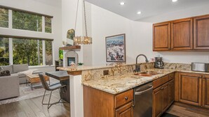 A modern kitchen with wooden cabinets, a granite countertop, and a built-in dishwasher. - Absolutely Darling Condo w/ Very Short Walk to Arrowhead Lift, Pool, Hot Tub!! (Edwards)