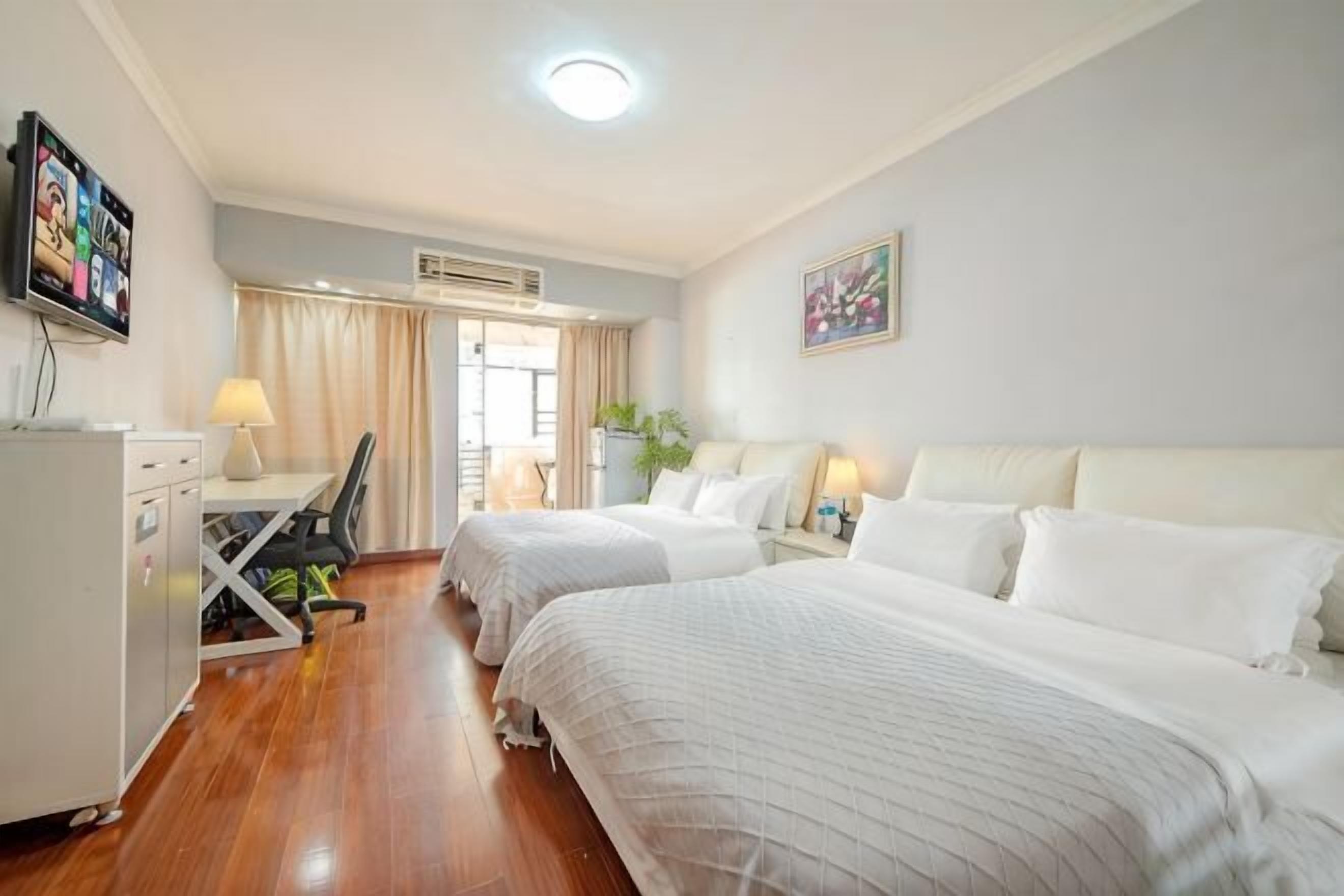 A hotel room with two beds, a desk, a chair, a TV, and a window with curtains.