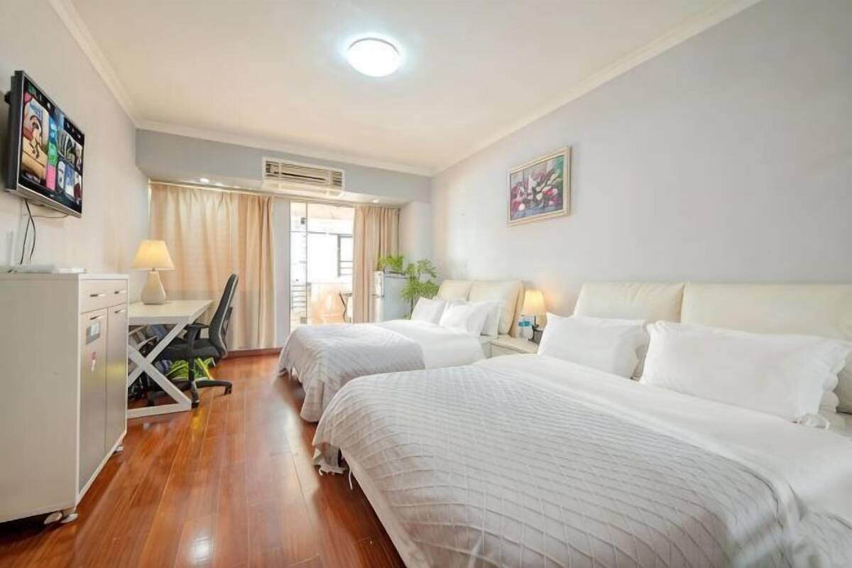 Une chambre d’hôtel avec deux lits, un bureau, une chaise, une télévision et une fenêtre avec des rideaux.