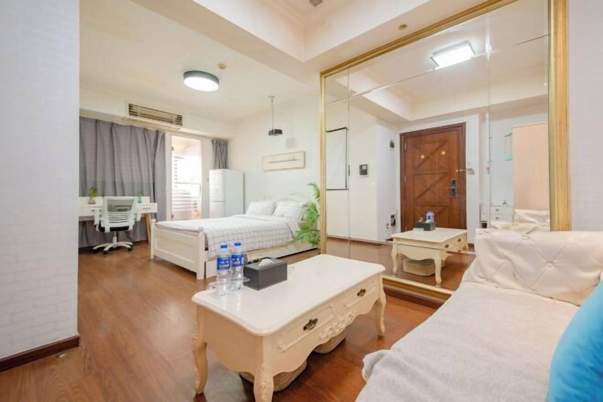 Une chambre d’hôtel comprenant un lit, un bureau, une chaise, une table de chevet et un grand miroir.
