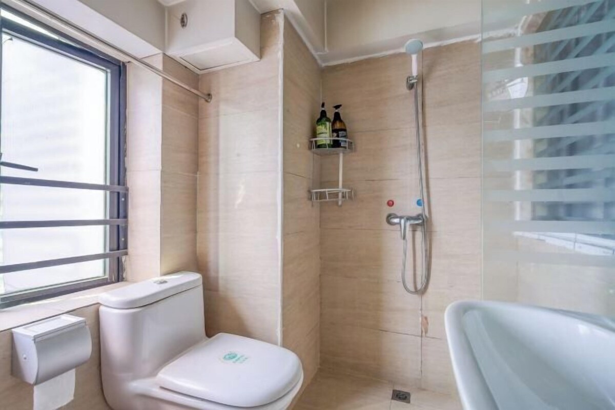 A bathroom with a toilet, a shower, and a window.