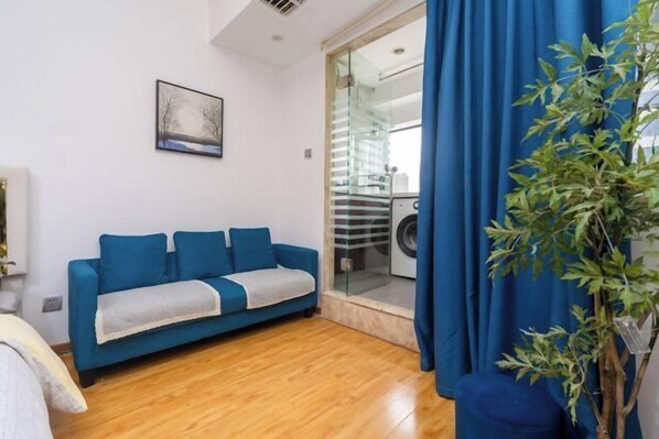 Un salon moderne avec un canapé bleu, une petite table et une plante en pot.