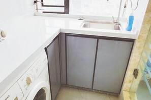 A compact kitchen with a washing machine, a sink, and a window.