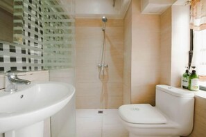 A bathroom with a white sink, toilet, and shower.