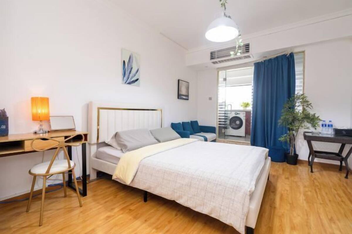 Une chambre à coucher moderne avec un lit, un bureau, une chaise et une plante en pot.