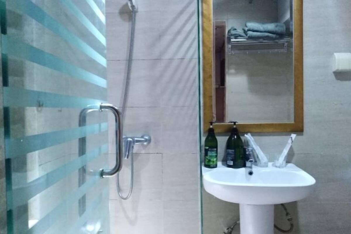 Une salle de bain avec une douche à parois de verre, un lavabo blanc et un miroir au-dessus.