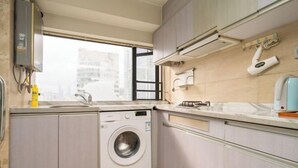 Eine kompakte Küche mit integriertem Waschtrockner, einem Fenster und einer wandmontierten Klimaanlage.