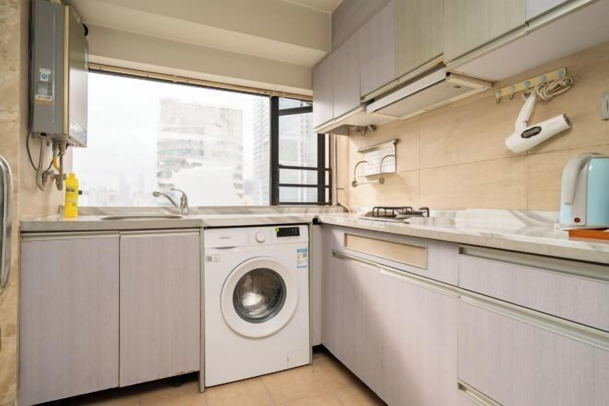 A compact kitchen with a built-in washer, a window, and a wall-mounted air conditioner.