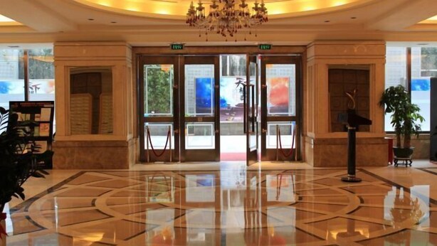 Eine Lobby mit einem Chandelier, doppelten Türen und einem polierten Boden.
