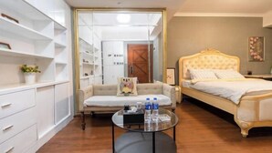 Ein Schlafzimmer mit Bett, Schlafsofa, Glastisch und Kleiderschrank.