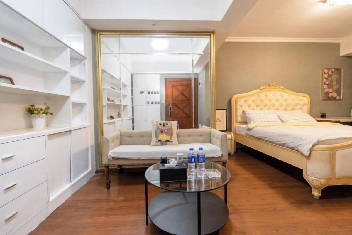 A bedroom with a bed, a sofa, a glass coffee table, and a wardrobe.