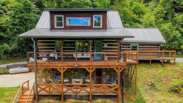 A two-story log cabin with a deck and outdoor seating area.
