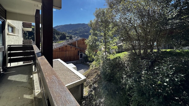 A balcony with a view of a wooden building and a hillside. - VIKING 23 - Village center apartment - Parking (La Clusaz)