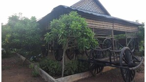 A traditional house with a sloped roof and a wooden structure with wheels.