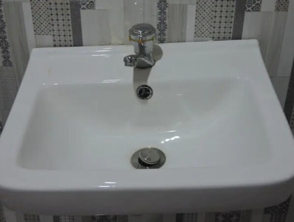 Un lavabo de salle de bain blanc, doté d’un robinet chromé et d’un bouchon d’évier.