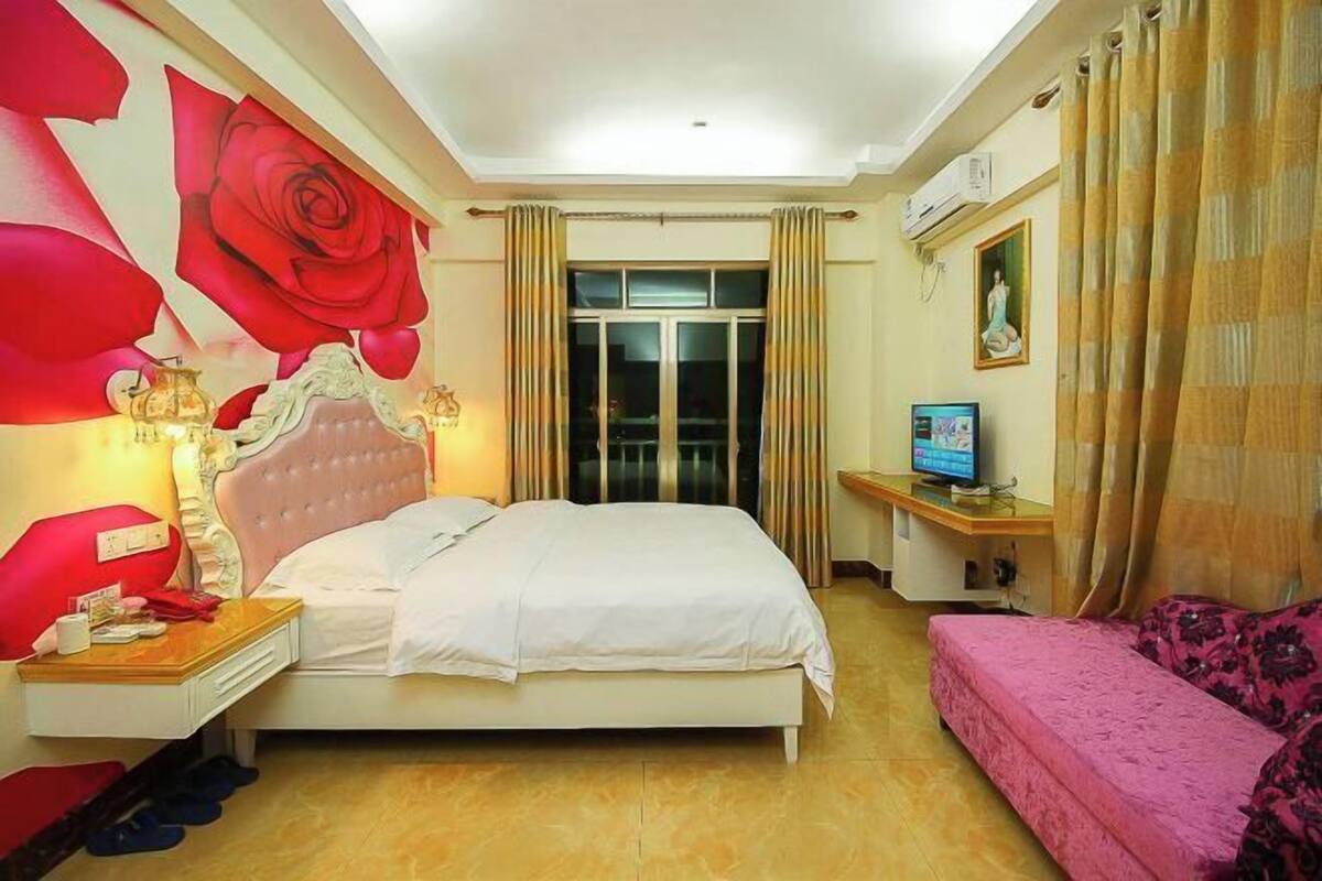 A hotel room with a bed, bedside table, lamp, TV, and a sofa.