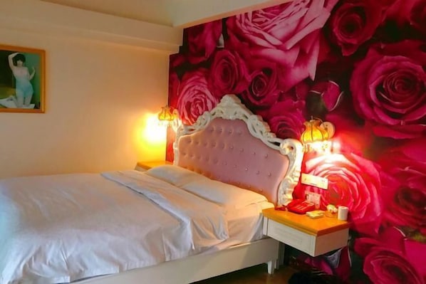 Un dormitorio con cama, mesita de noche y una pared con estampado floral.