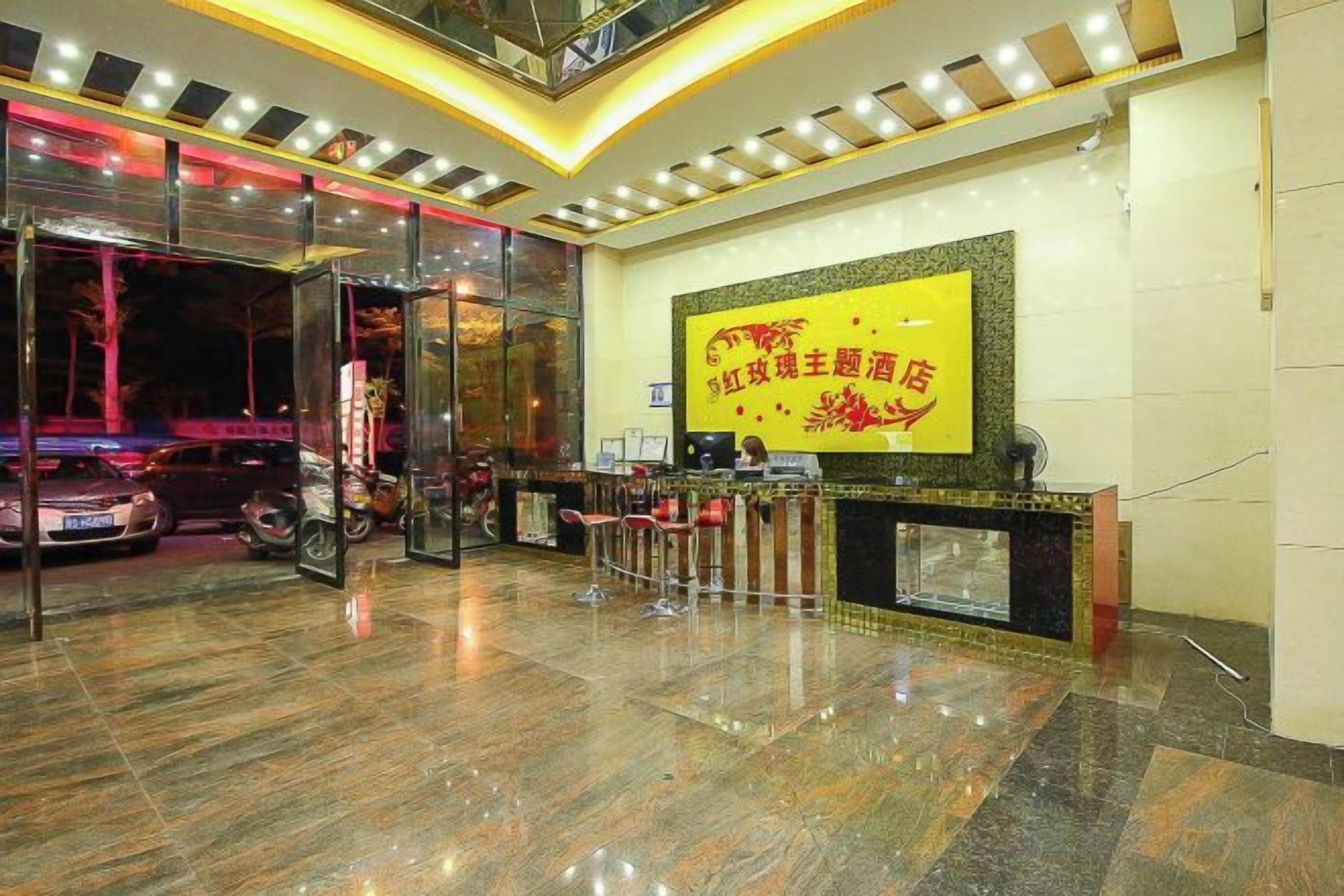 A hotel reception area with a glass entrance, a reception desk, and a large screen displaying text.