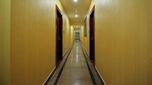 Ένας μακρύς, στενός διάδρομος ξενοδοχείου με ξύλινα τοιχώματα και πλακάκι στο δάπεδο.