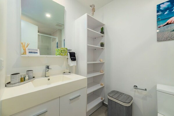 Een moderne badkamer met een wit wastafelmeubel, spiegel en planken.