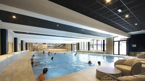 Una piscina interior con varias pistas de natación, rodeada de zonas de descanso y grandes ventanales.