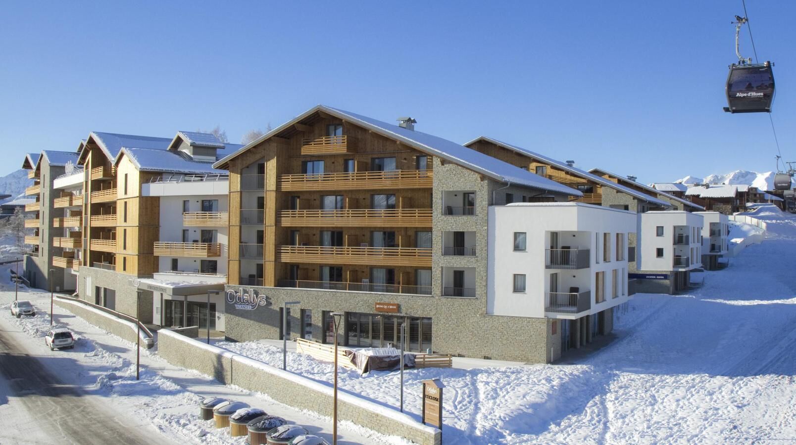 A modern multi-story hotel with a ski lift in the background.