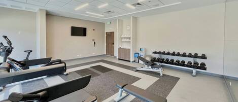 A modern gym with treadmills, a bench press, and dumbbells.