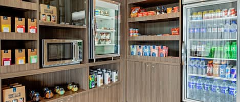Eine Küchenzeile mit einer Mikrowelle, einem Kühlschrank und Regalen, gefüllt mit Gewürzen und Getränken.