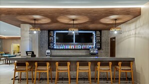 A bar area with a long counter, multiple bar stools, and pendant lighting. - Fairfield by Marriott San Jose Airport Alajuela (Rio Segundo)