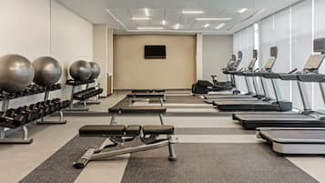 A gym with treadmills, elliptical machines, and free weights.