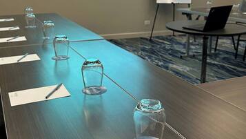 Un salón de conferencias con una larga mesa, una pantalla de proyector mostrando 'Fairfield by Marriott' y una pizarra.