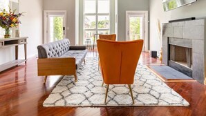 A modern living room with a sofa, armchair, fireplace, and large windows. - Greystone, 3500 sq ft, Rooftop Access, Sleeps 16 (Chicago)