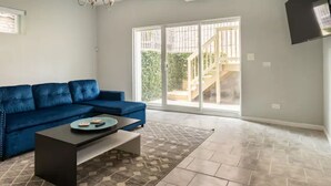 A living room with a blue sofa, a coffee table, and a patterned rug. - Greystone, 3500 sq ft, Rooftop Access, Sleeps 16 (Chicago)
